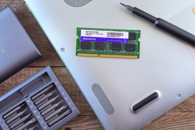 Laptop deschis pe un birou de service, cu un SSD nou pregătit pentru montare