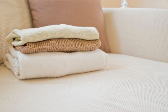 Pulovere împăturite și așezate în cutii de depozitare din material textil, pregătite pentru sezonul următor